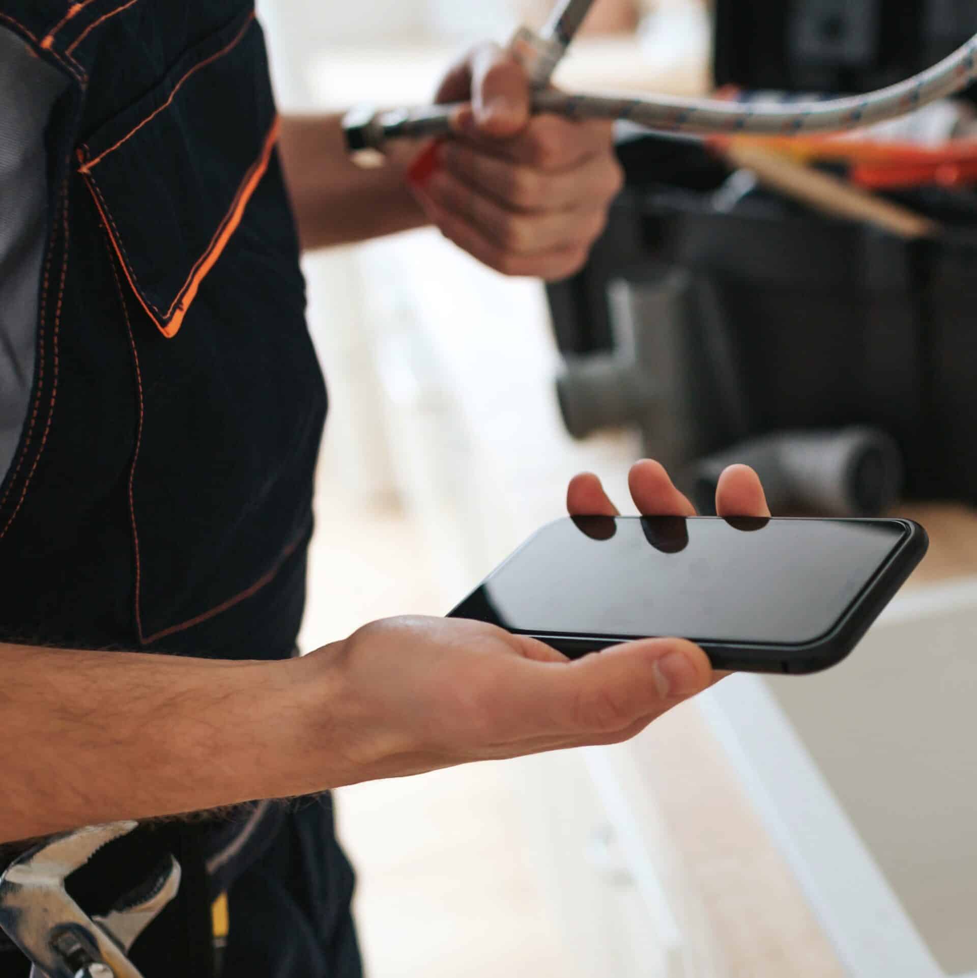 man standing in kitchen at sink, holding a phone