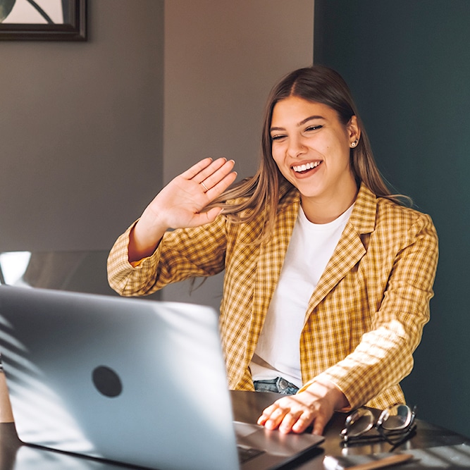 Portrait of happy stylish brunette young woman sitting at table on her laptop