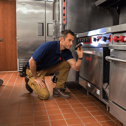restaurant safety advisor conducting inspection with their flashlight on the industrial cooktops