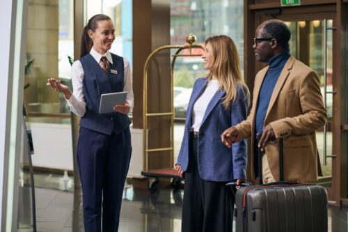 hotel manager in uniform with tablet greeting hotel guests