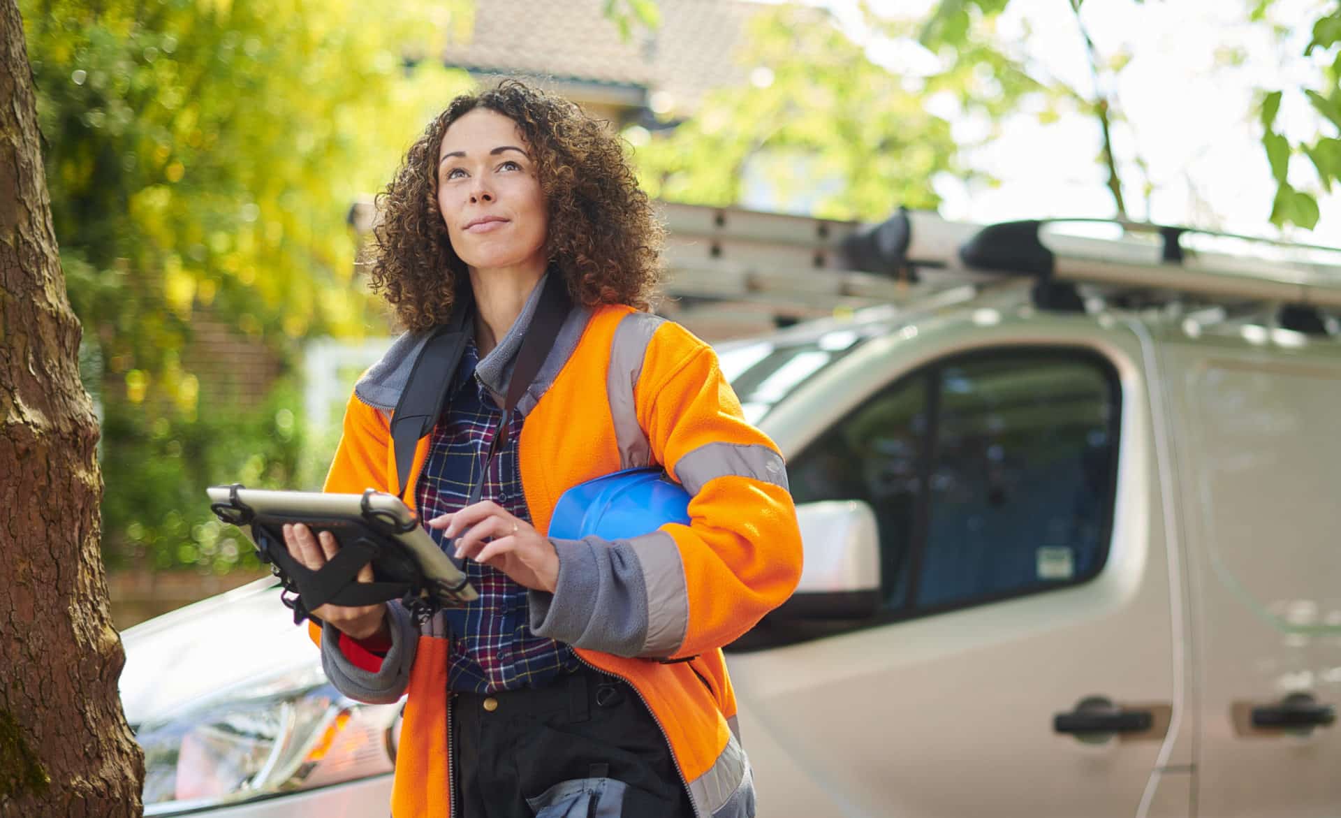 young professional site inspector in orange vest entering information to a tablet