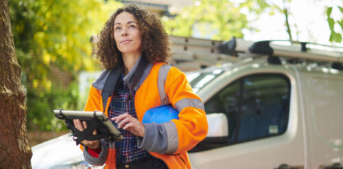 professional female inspector in orange safety vest with tablet finishing a site inspection
