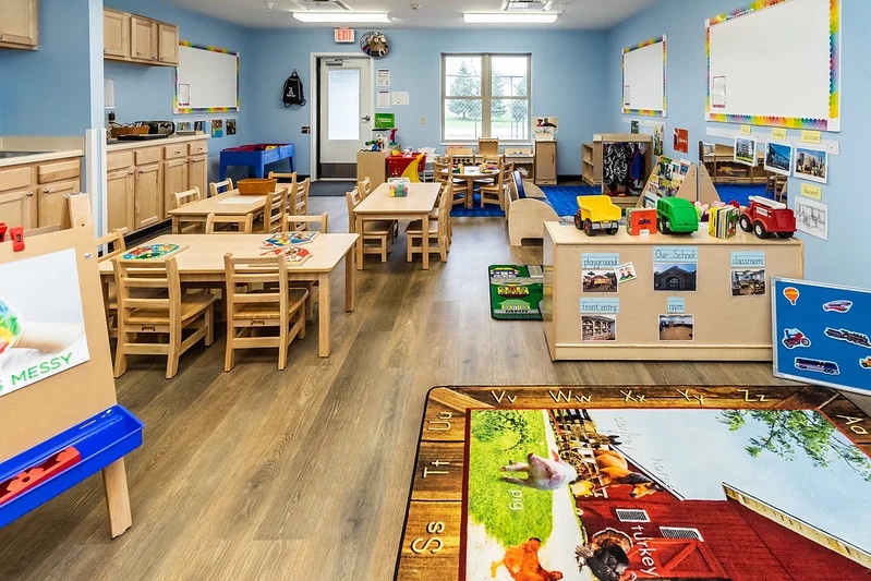 young kindergartner classroom with tables and boards laid out with pictures and toys