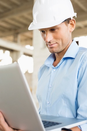 young male contractor looking at his laptop for information