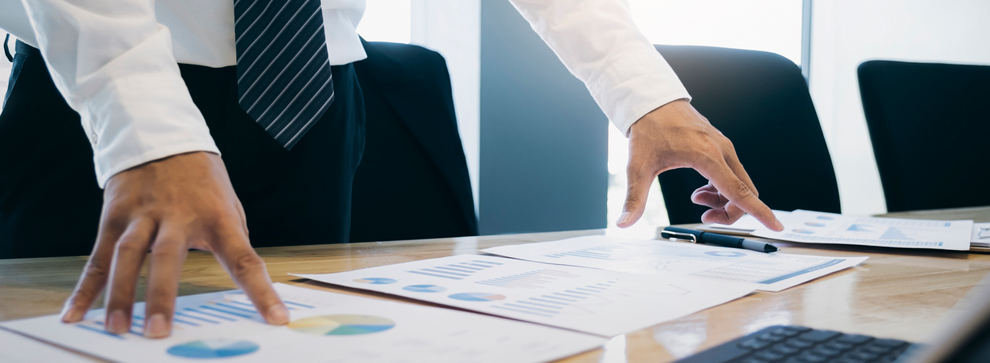 business professional looking down at a tabletop of various printouts, comparing them