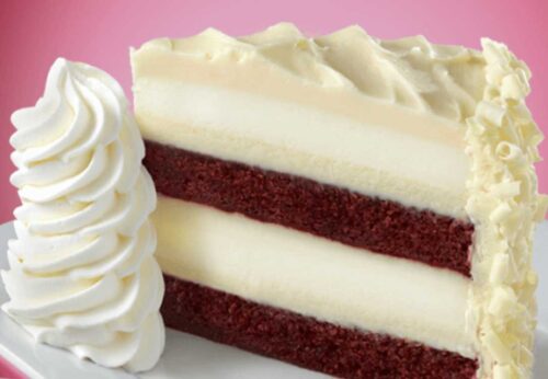 decadent red velvet cheesecake frosted and plated against a pink background