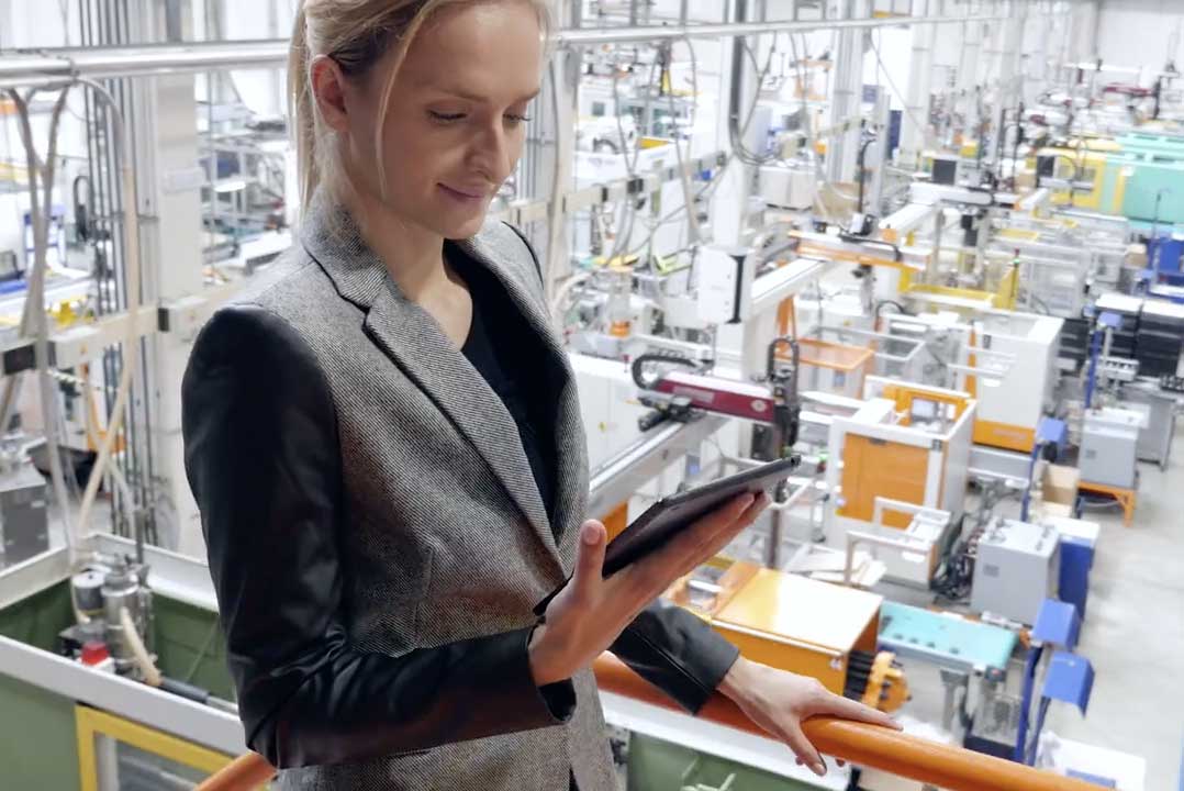 young professional woman overlooking a production facility reading information from her tablet