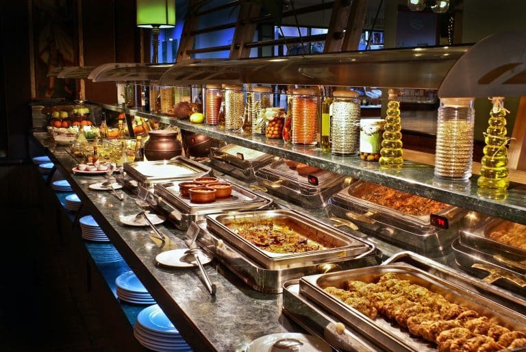 hot bar at a buffet, laid out with plates and silverware available