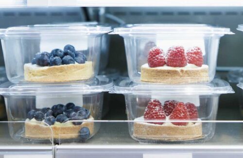 containers of blueberry and raspberry tarts in a fridge