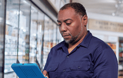 middle aged service provider reporting information into a tablet within a grocery store