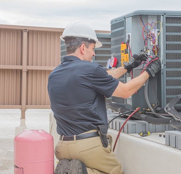 asset-management-replacement worker on roof repairing hvac unit