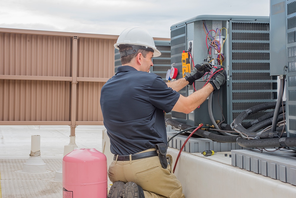HVAC technician inspecting a rooftop mounted condenser
