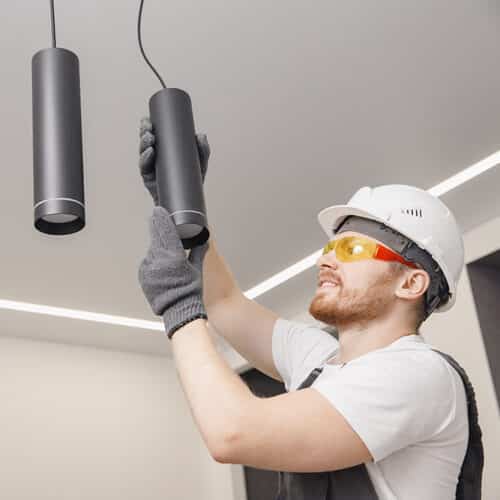 electrician finishing installation of lights within residential interior