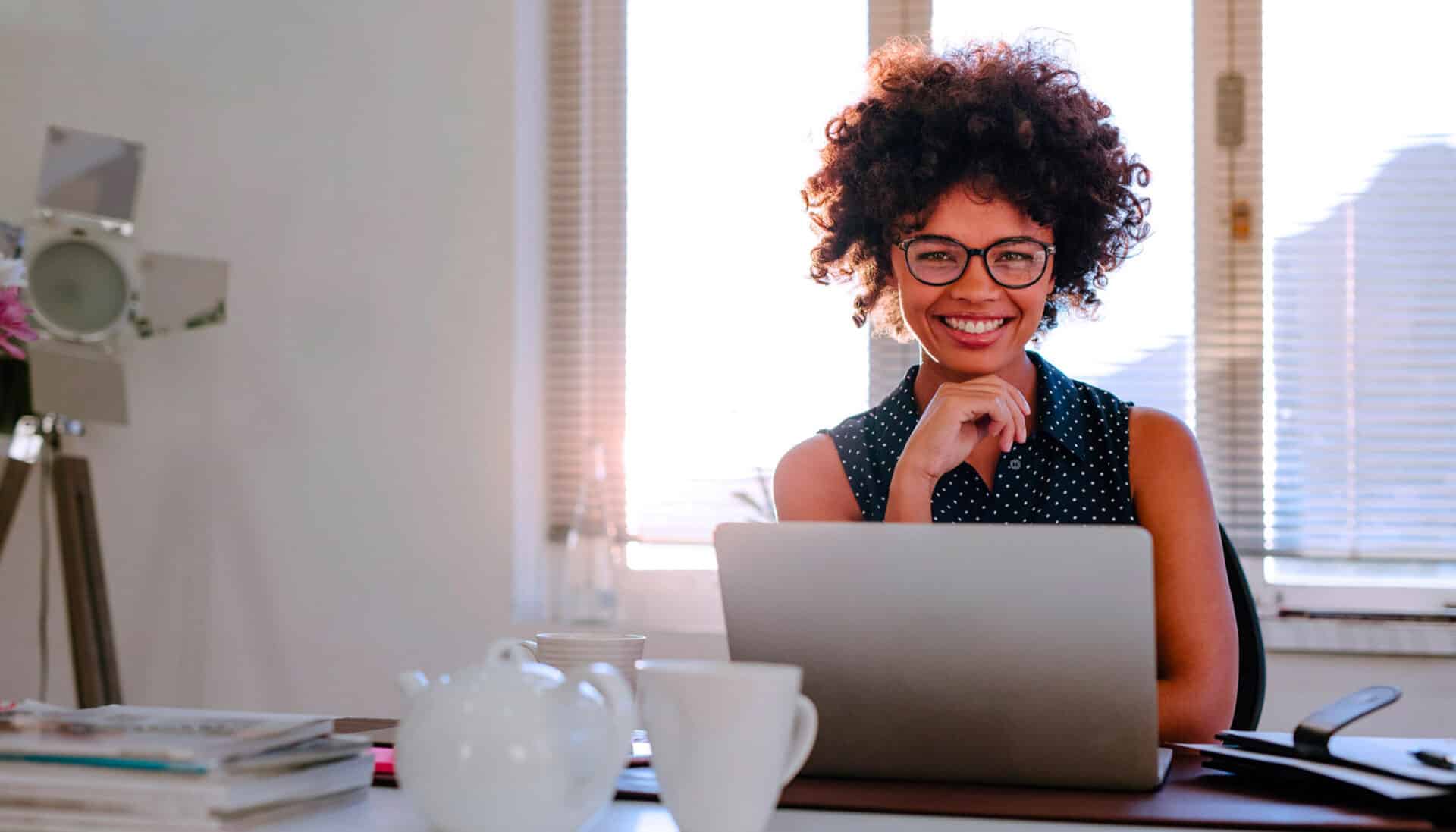 Woman in office using laptop and GenAI for seasonal planning.