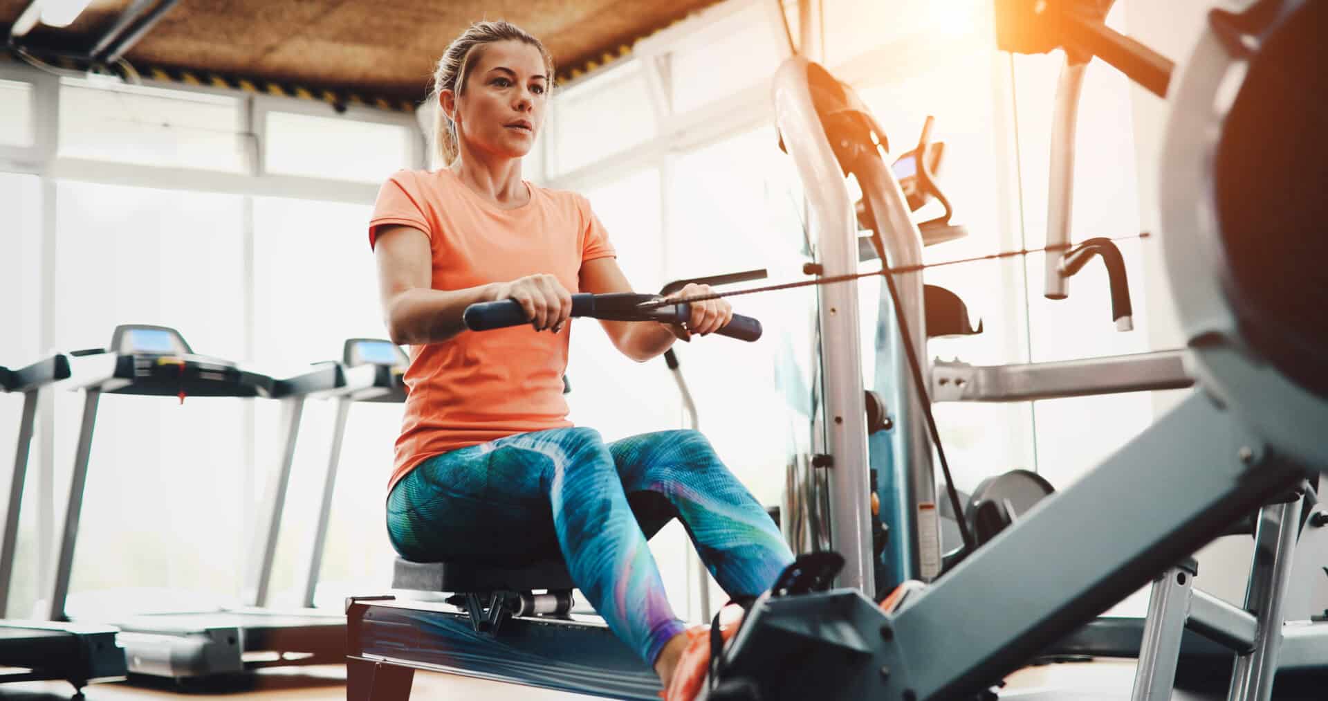 Woman working out on rowing machine in fitness center.