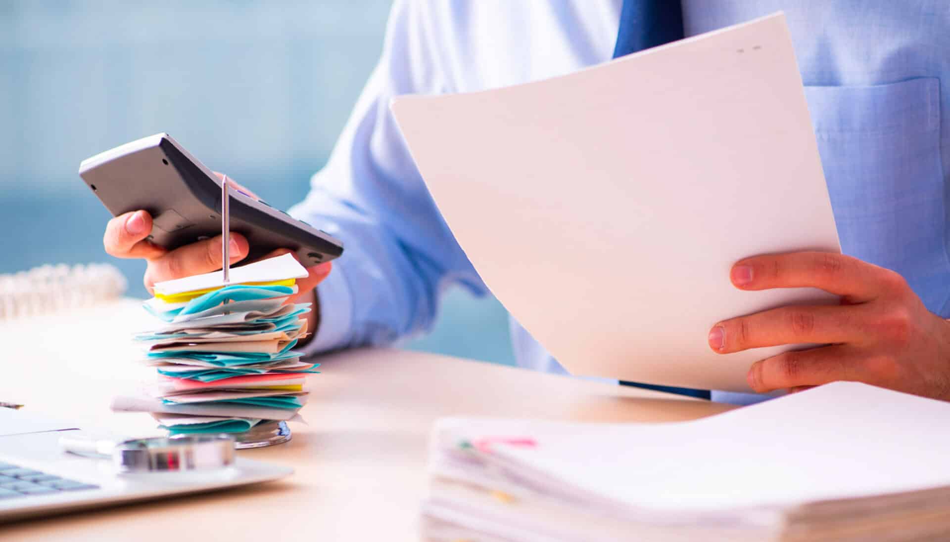 Person using a calculator and reading notes.