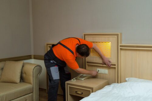 Maintenance-worker-repairing-electric-socket-hotel-room